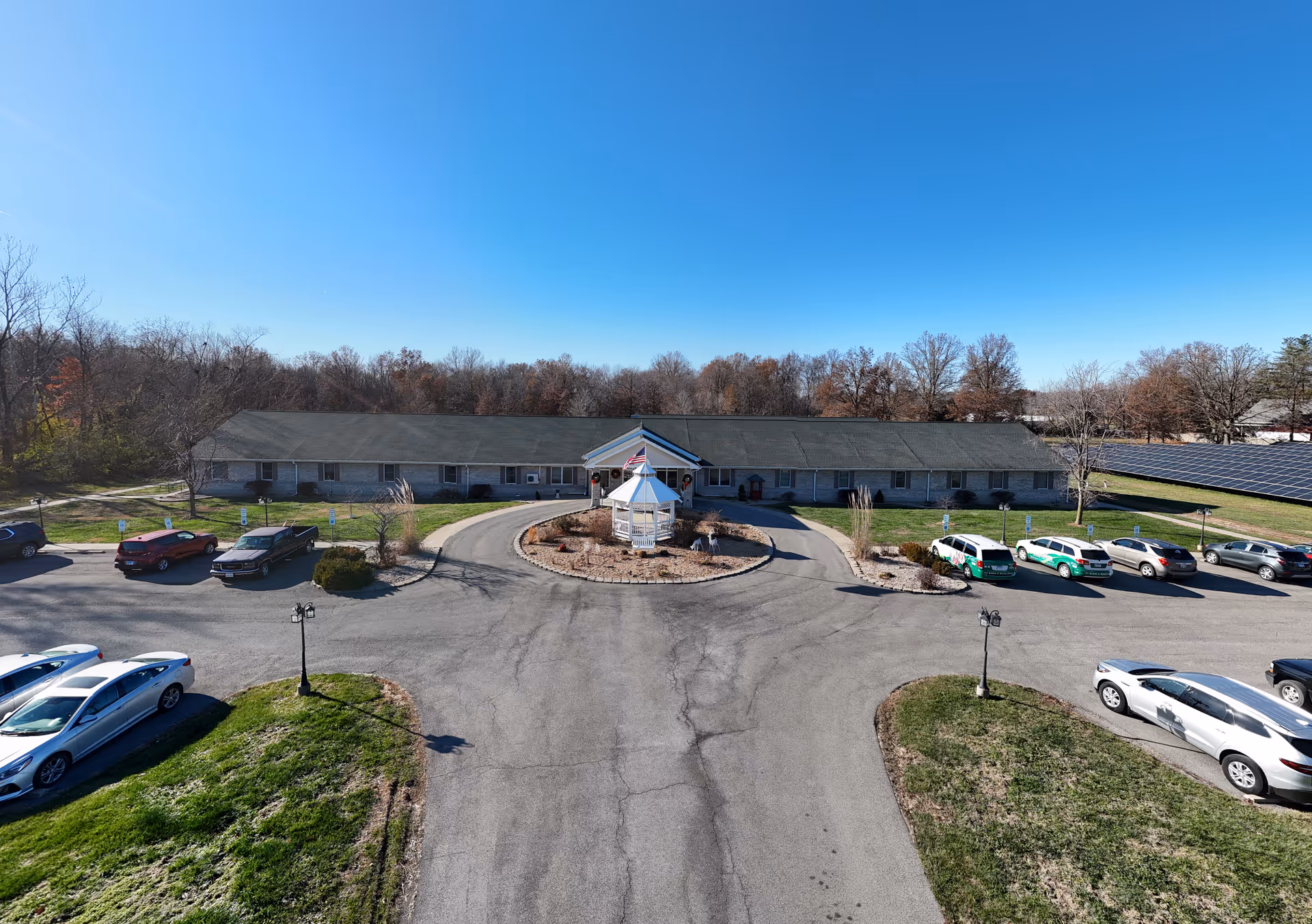 Front view of a single-story senior living facility with circular driveway and gazebo.