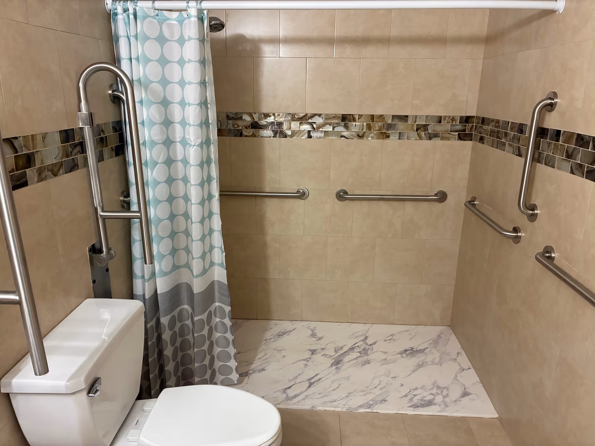 Accessible bathroom with tiled walls, a shower curtain, and multiple grab bars.