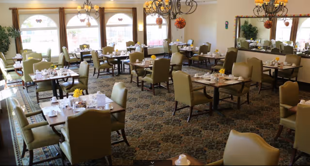 A spacious dining room at Villa Fontana Retirement Community with many tables and chairs.