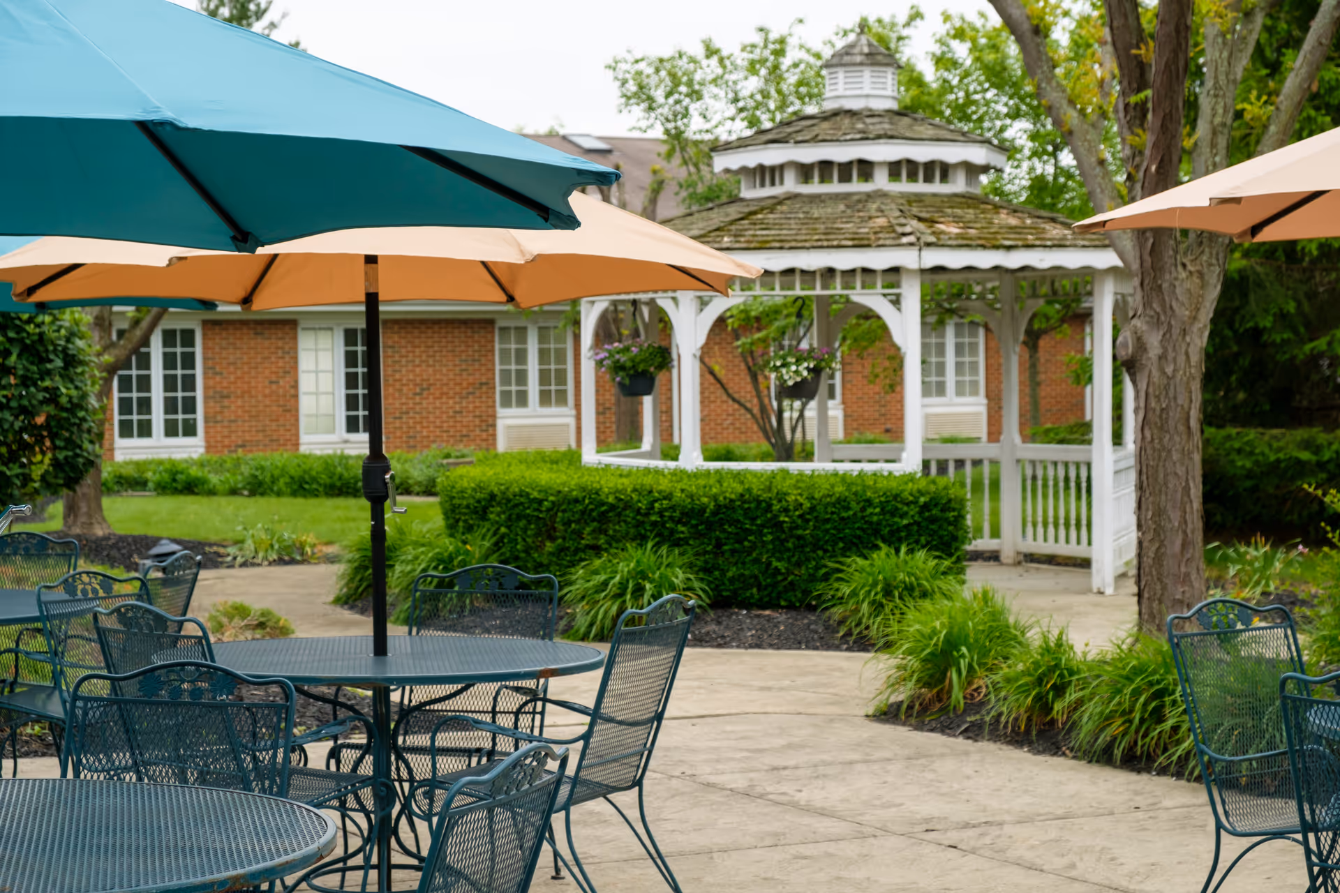 Outdoor patio with metal tables, chairs, umbrellas, and a white gazebo.