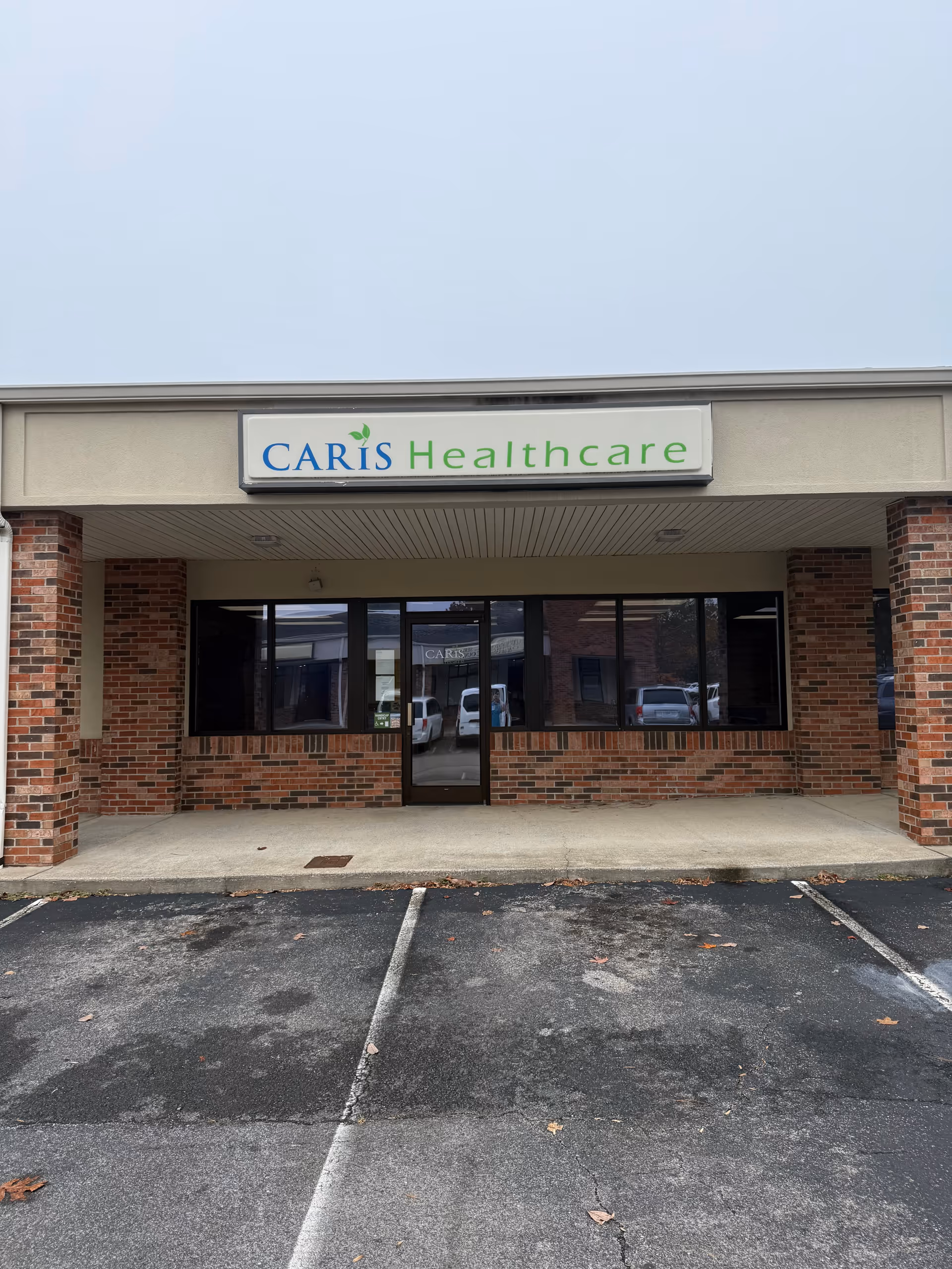 Brick storefront with Caris Healthcare sign and glass entrance door.