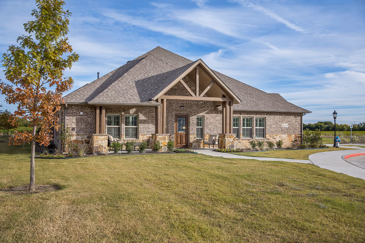 Brick senior living facility with stone accents, front entrance, and manicured lawn.