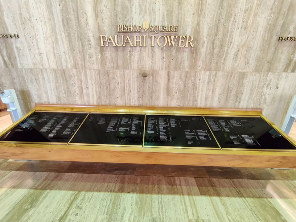 Marble lobby wall with Bishop Square Pauahi Tower sign and a long glass display case.