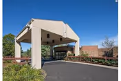 Exterior entrance with a covered drop-off and driveway at a senior facility.