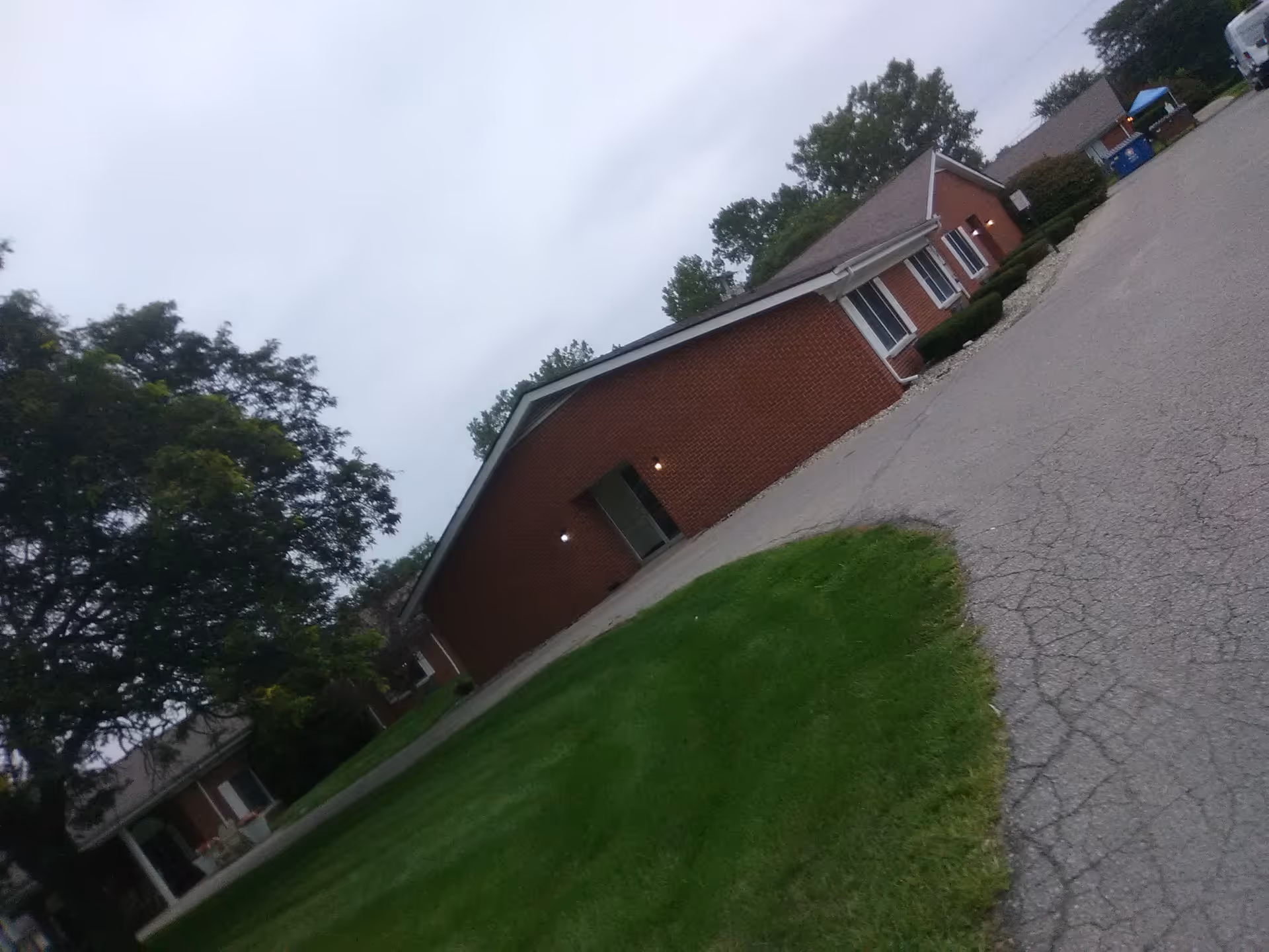 Red brick senior living facility exterior with a driveway and lawn.