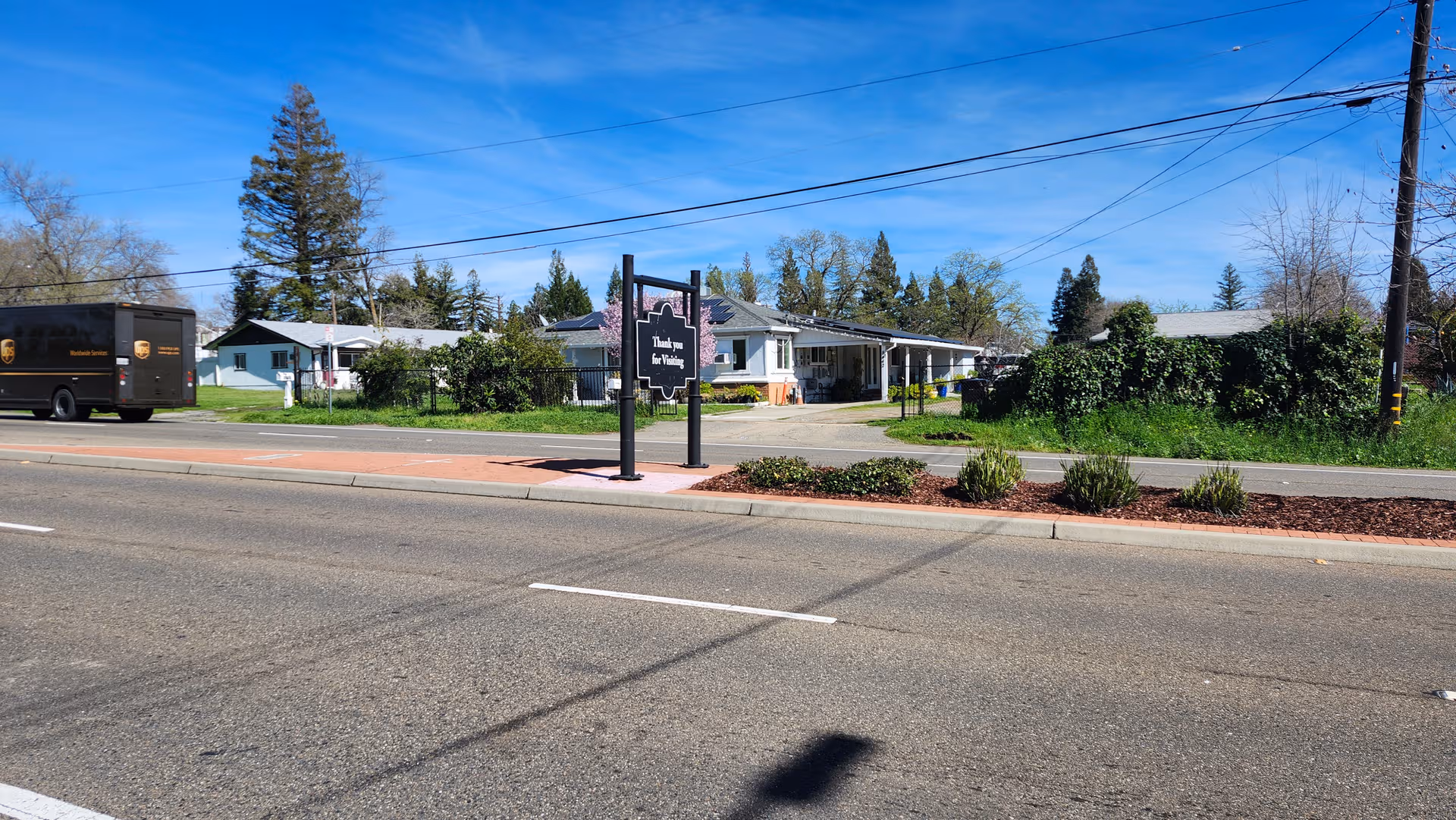 Exterior view of a care home along a street with a front sign.