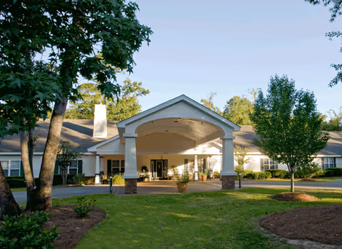 Front exterior of Oaks at Charleston senior living facility with covered entrance and landscaped grounds.