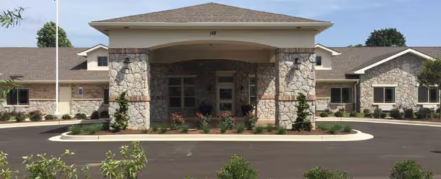 Stone Creek Memory Care building entrance with stone columns and landscaped circular driveway.