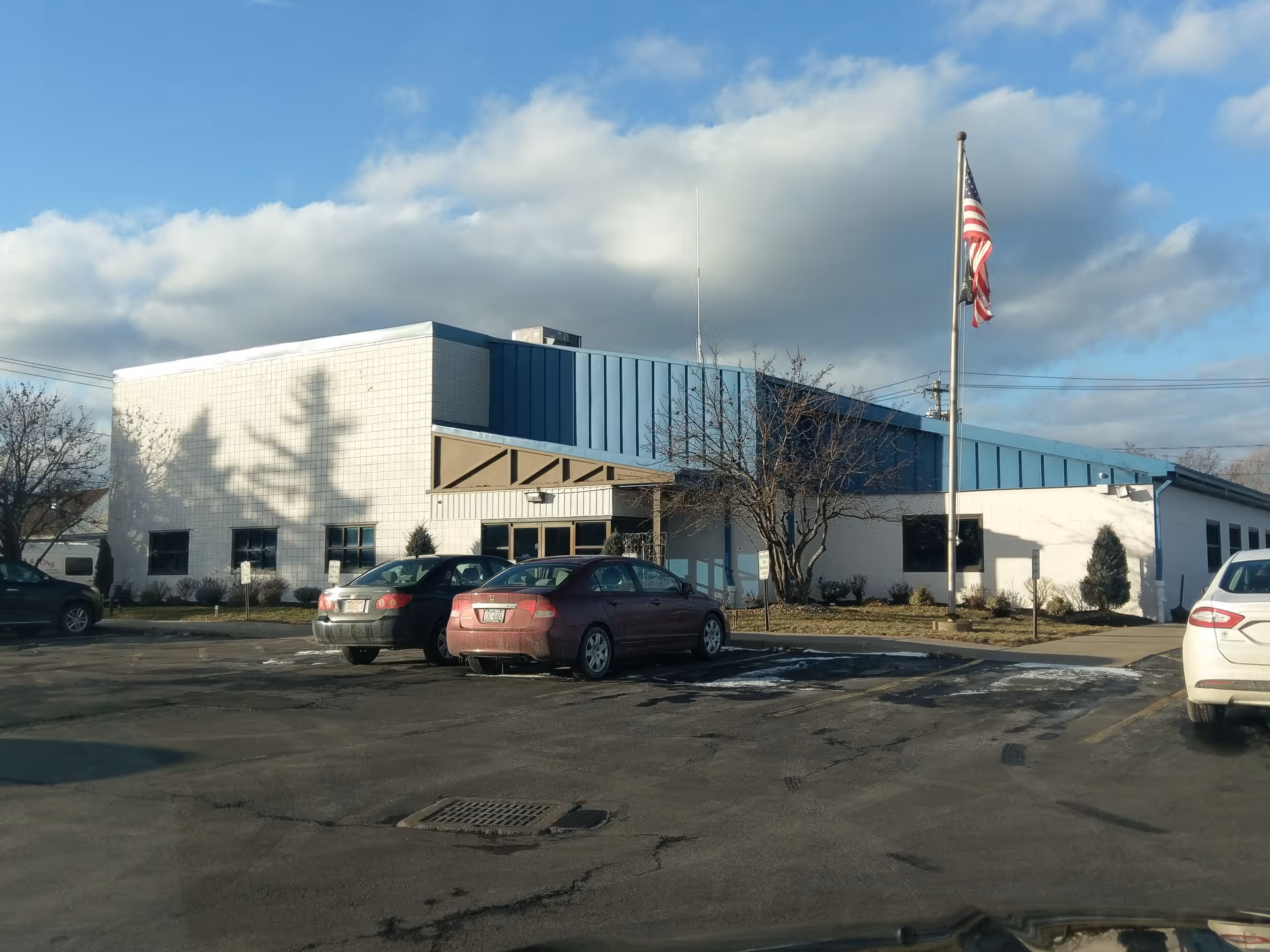 Exterior view of Venture Forthe Niagara Falls Office and Training Center with flagpole and parked cars.