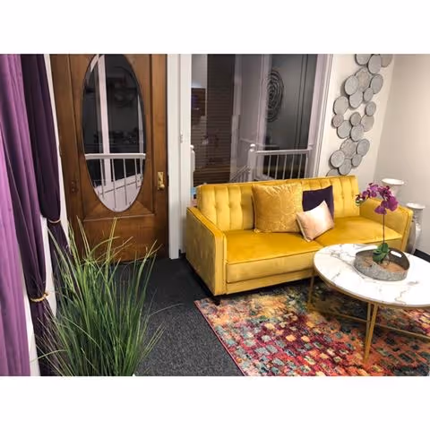 Bright yellow sofa with purple curtains and a round coffee table in a cozy living room.