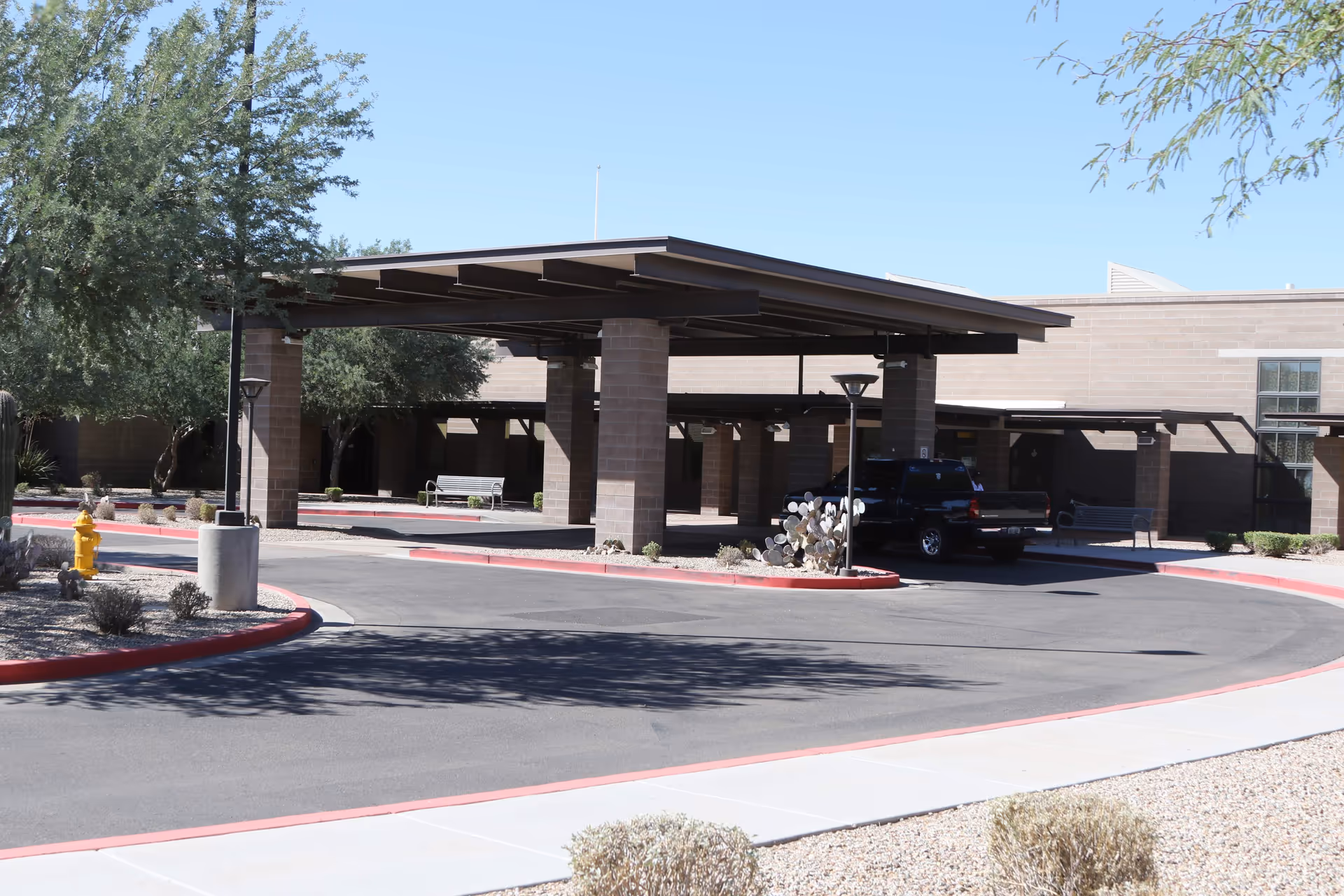 Exterior view of a senior care center entrance with a covered drive-through and parking.