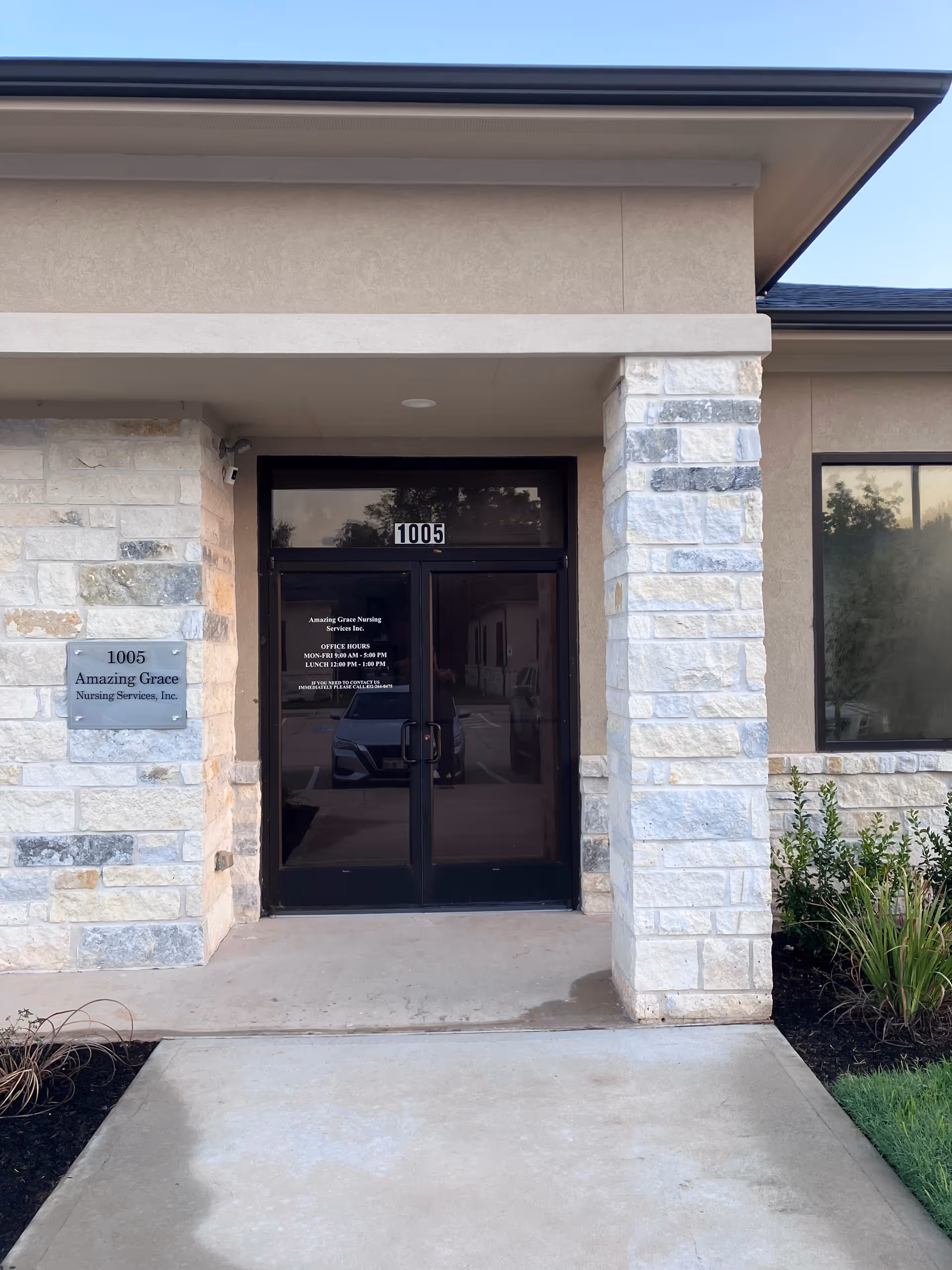 Front entrance of Amazing Grace Nursing Services building with stone pillars and glass doors.