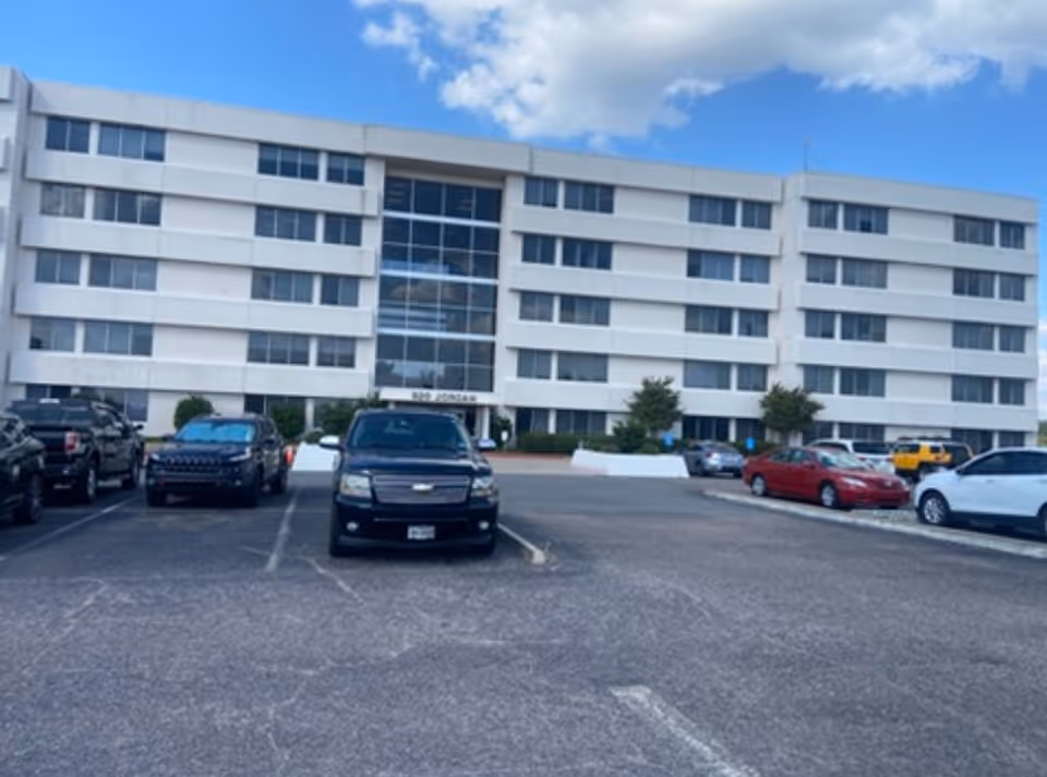 Front view of a multi-story senior living building with a spacious parking lot.