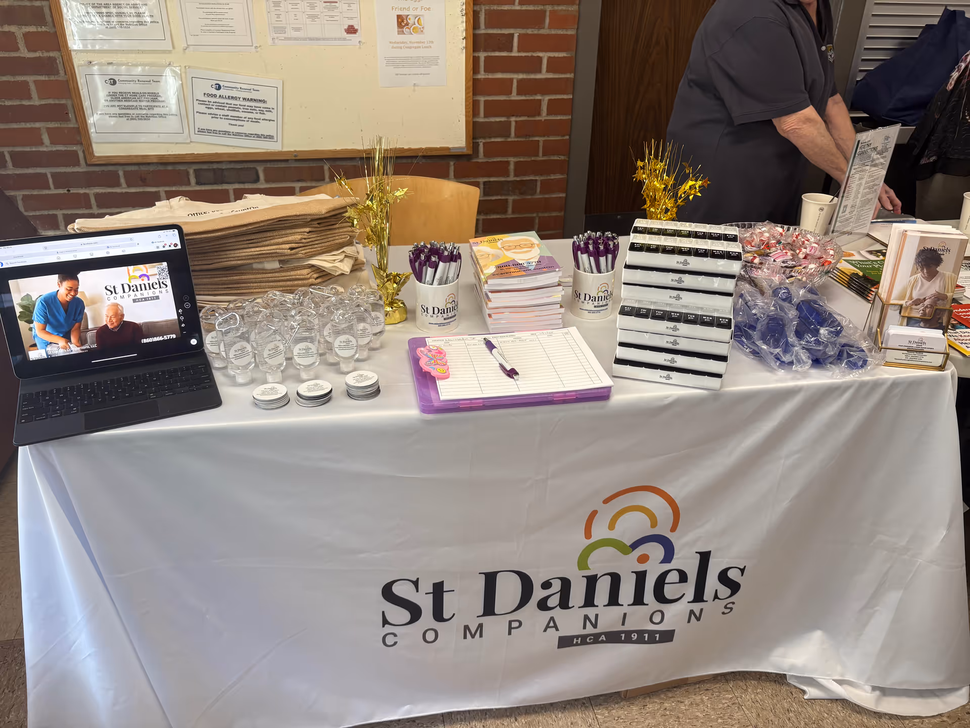 Promotional information table for St Daniels Companions with brochures, pens, and a laptop.