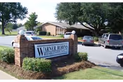 Exterior view of Warner Robins Rehabilitation Center with brick entrance sign and parked cars.