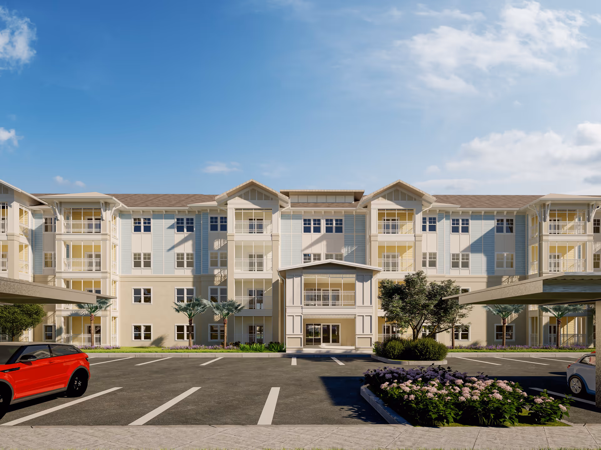 Front exterior of a multi-story senior living building with balconies, a covered entrance, parking spaces and landscaped flowerbeds under a blue sky.