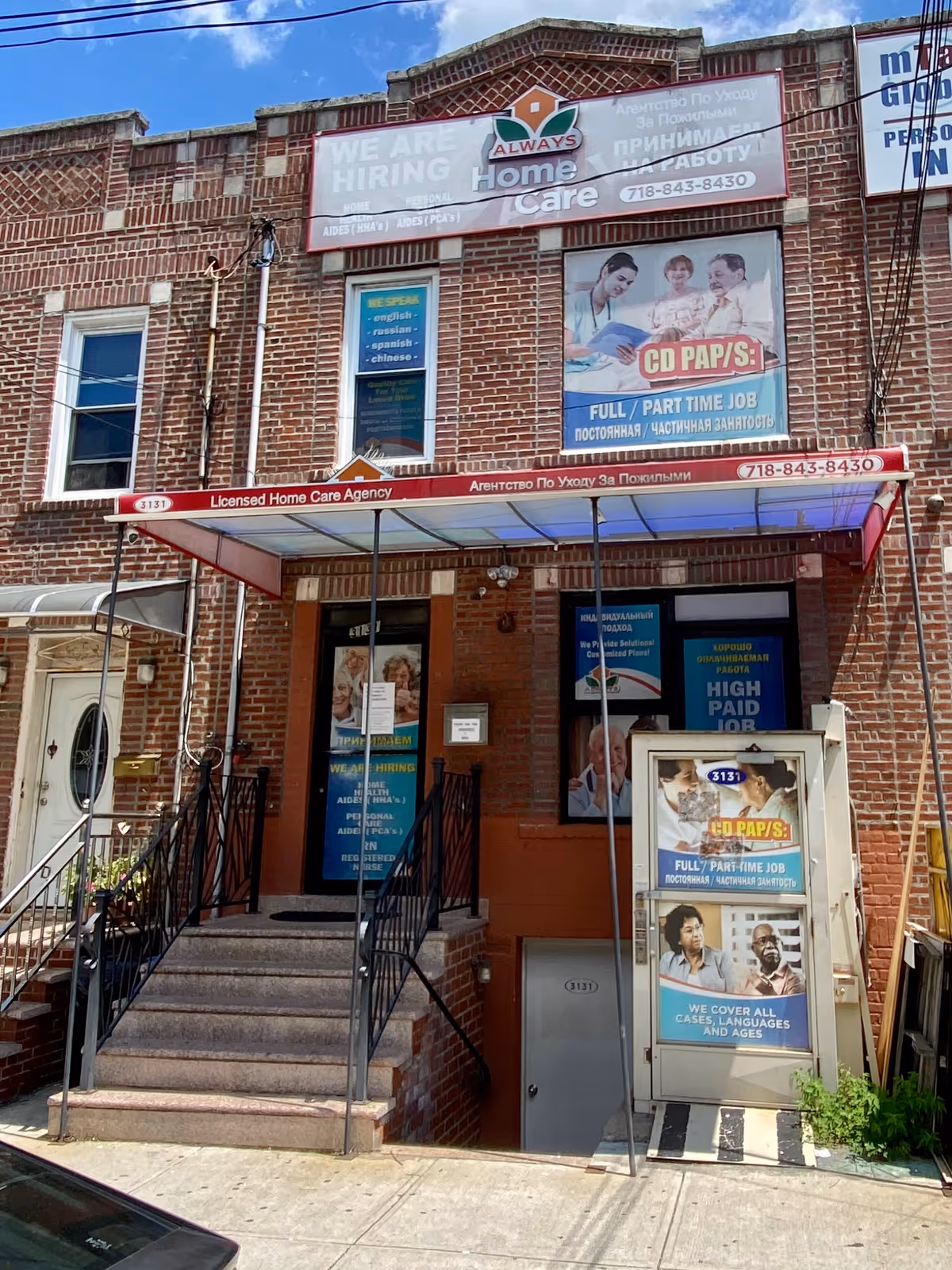 Brick building facade with banners and an awning advertising Always Home Care, front entrance stairs.