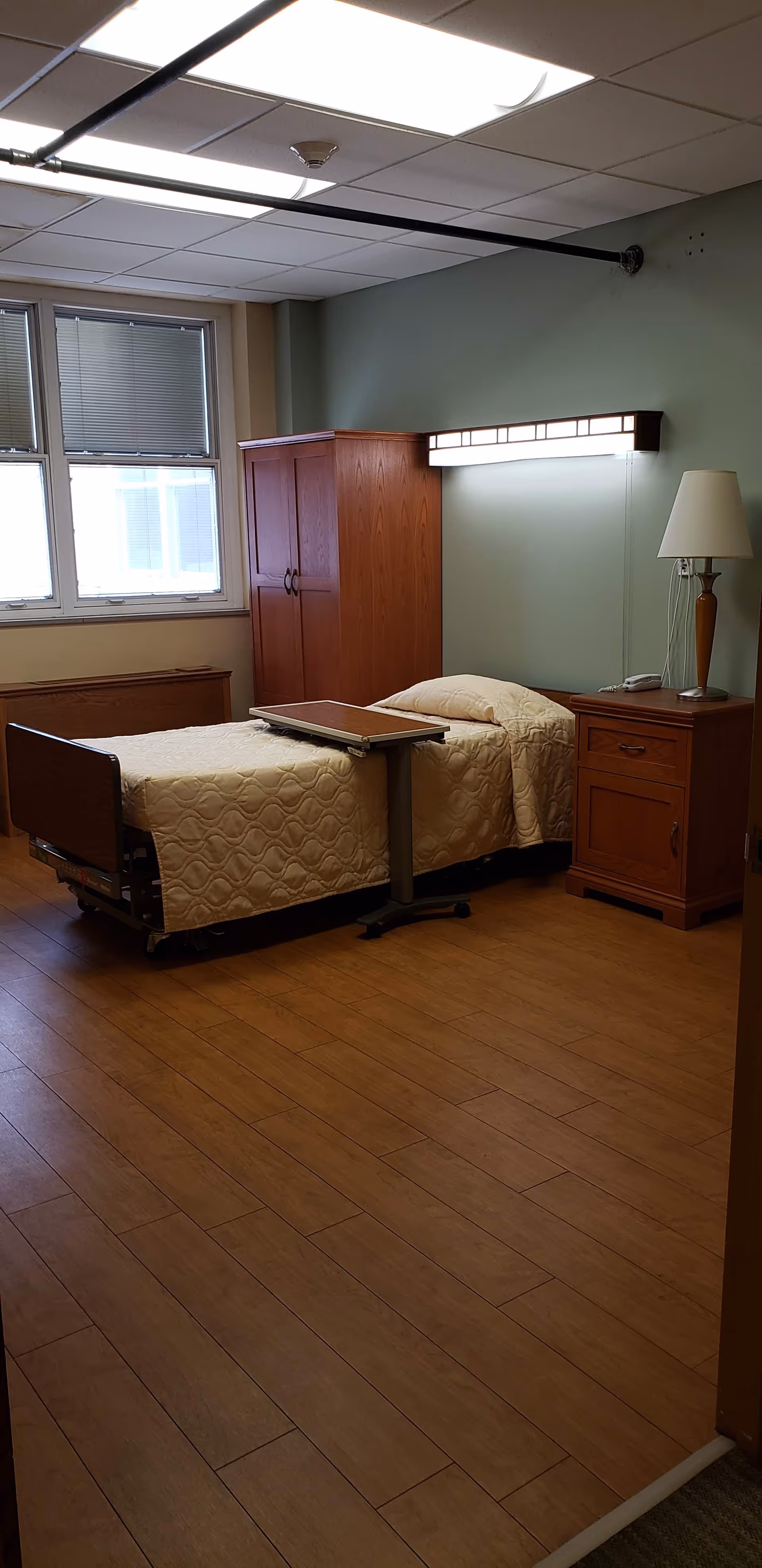 A bedroom with two twin beds, matching wood furniture, and an overbed table.