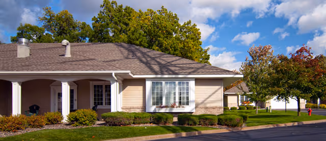 Exterior view of Augustana Emerald Crest III, a single-story facility with beige siding and landscaping.