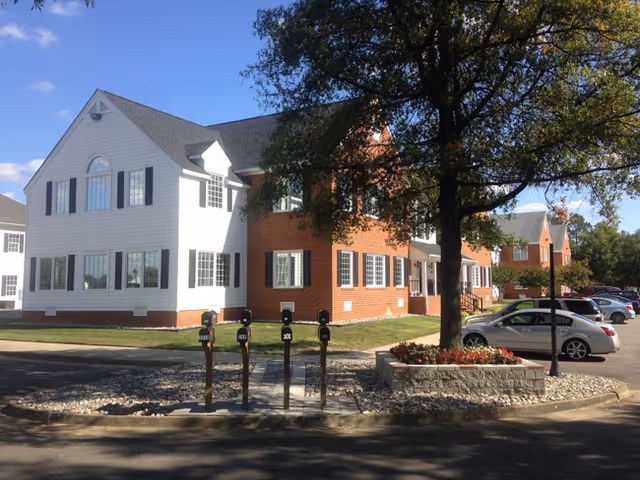 Exterior view of Covenant Home Care building with white and brick facade, trees, and parking.