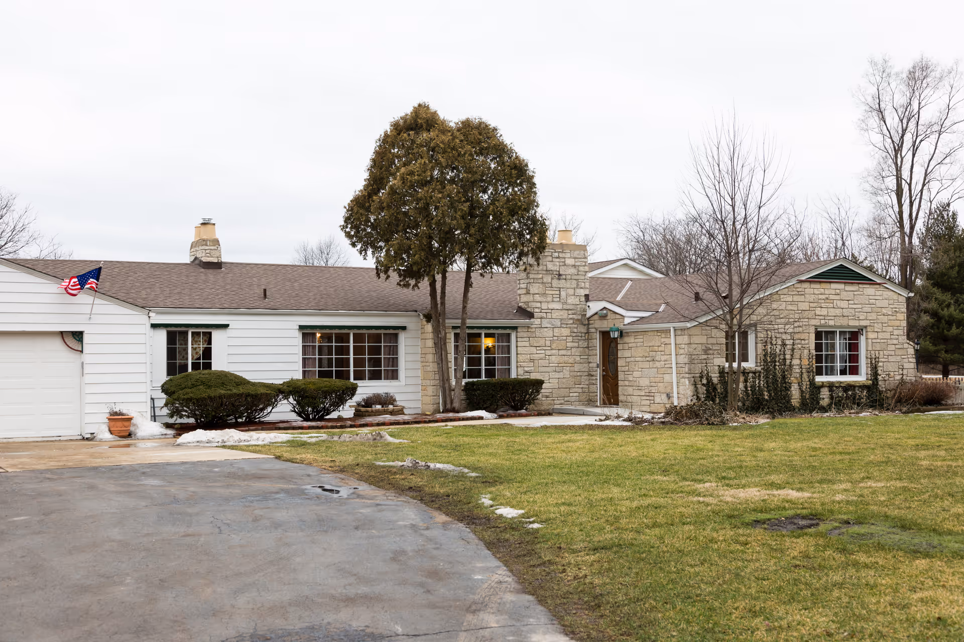 Front exterior of a single-story senior living facility with stone accents and a lawn.
