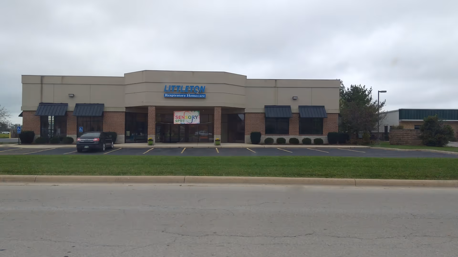 Exterior view of a medical equipment facility with brick-and-beige facade and parking.