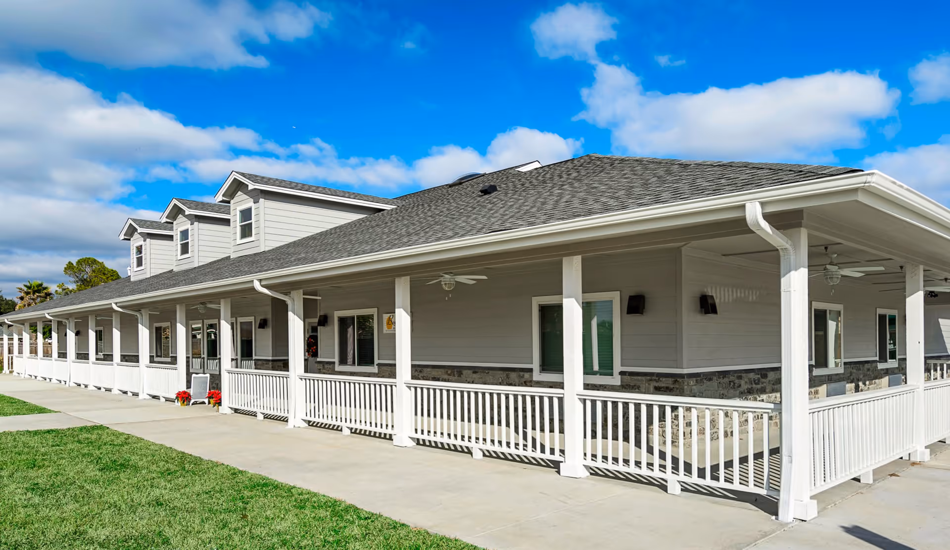 Exterior view of Beehive Homes of Cypress Texas with a long porch and white railings.