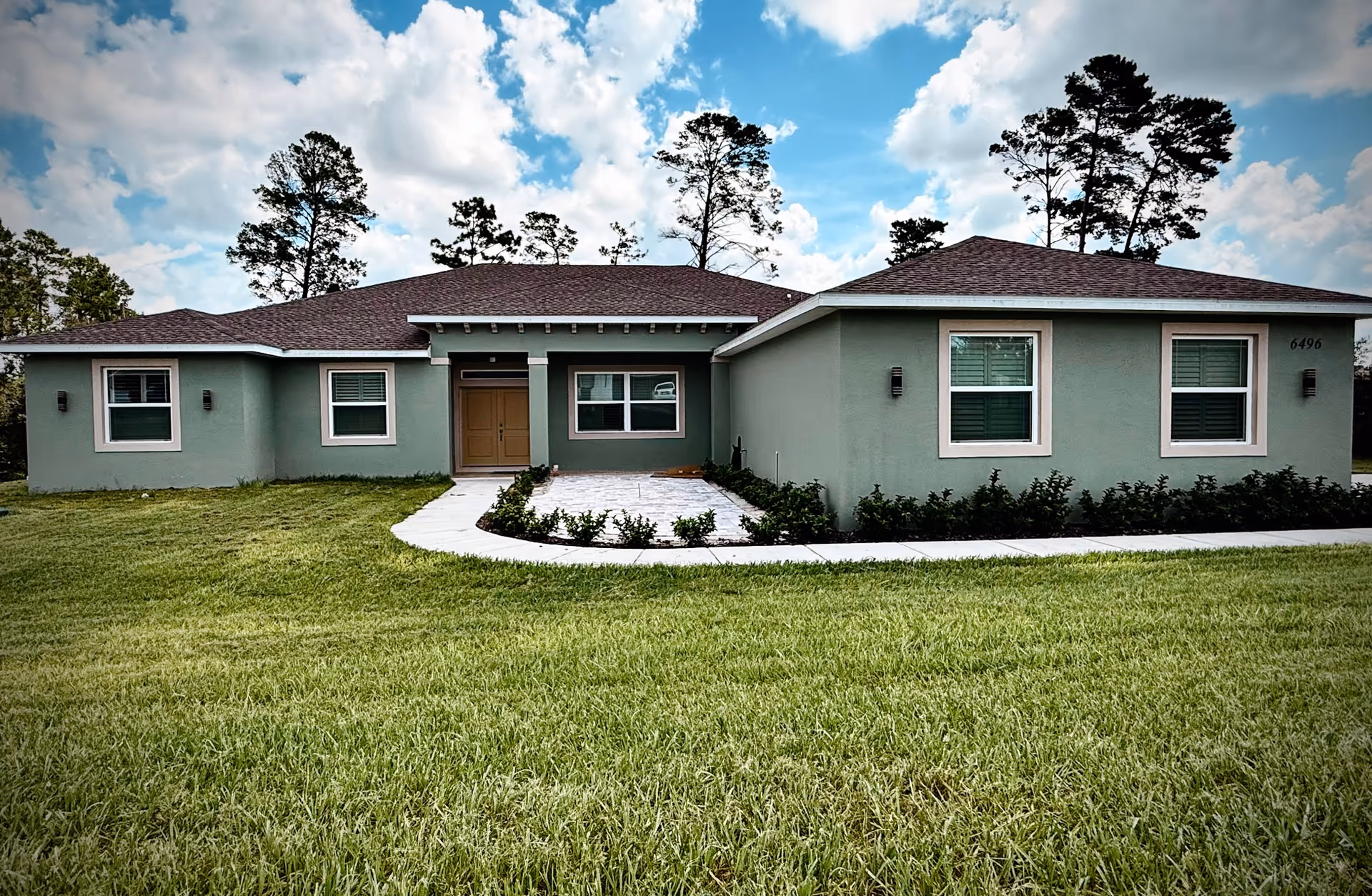 Single-story mint green senior living facility exterior with curved walkway and lawn.