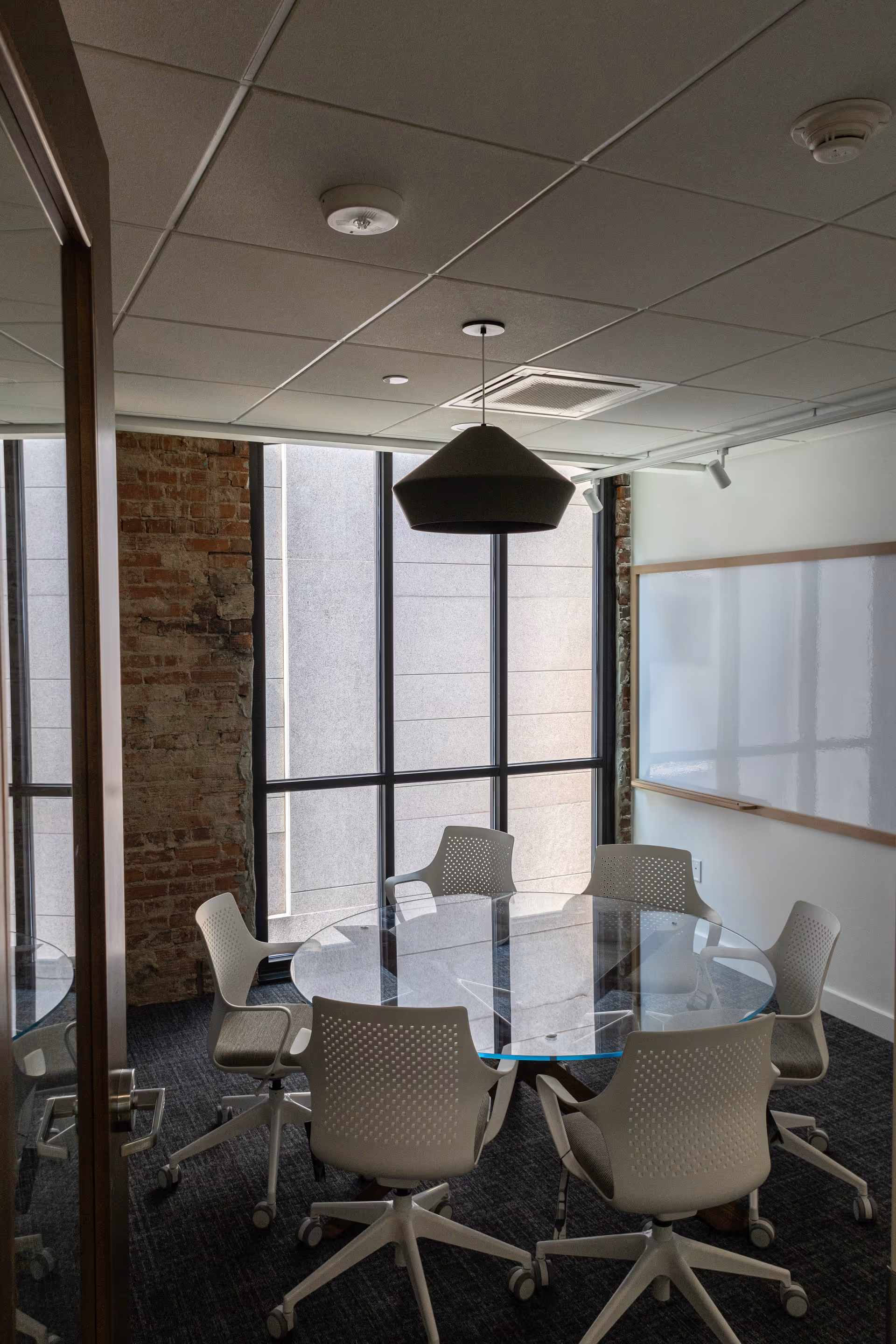 Glass round conference table with white chairs in a bright, modern meeting room.