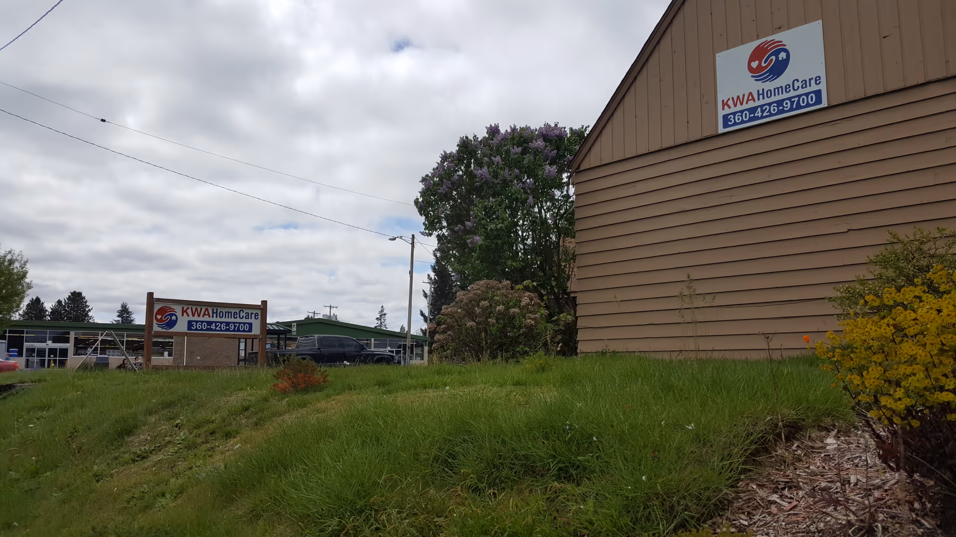 Exterior view of a beige senior care building with KWA HomeCare signs and grassy lawn.