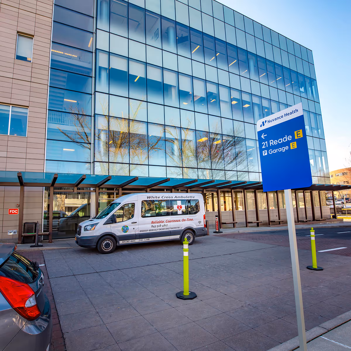 Exterior view of a glass-front medical building with a parked van and signage.