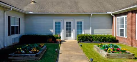 Exterior view of a Brookdale Sugar Land building with a central walkway and garden beds.