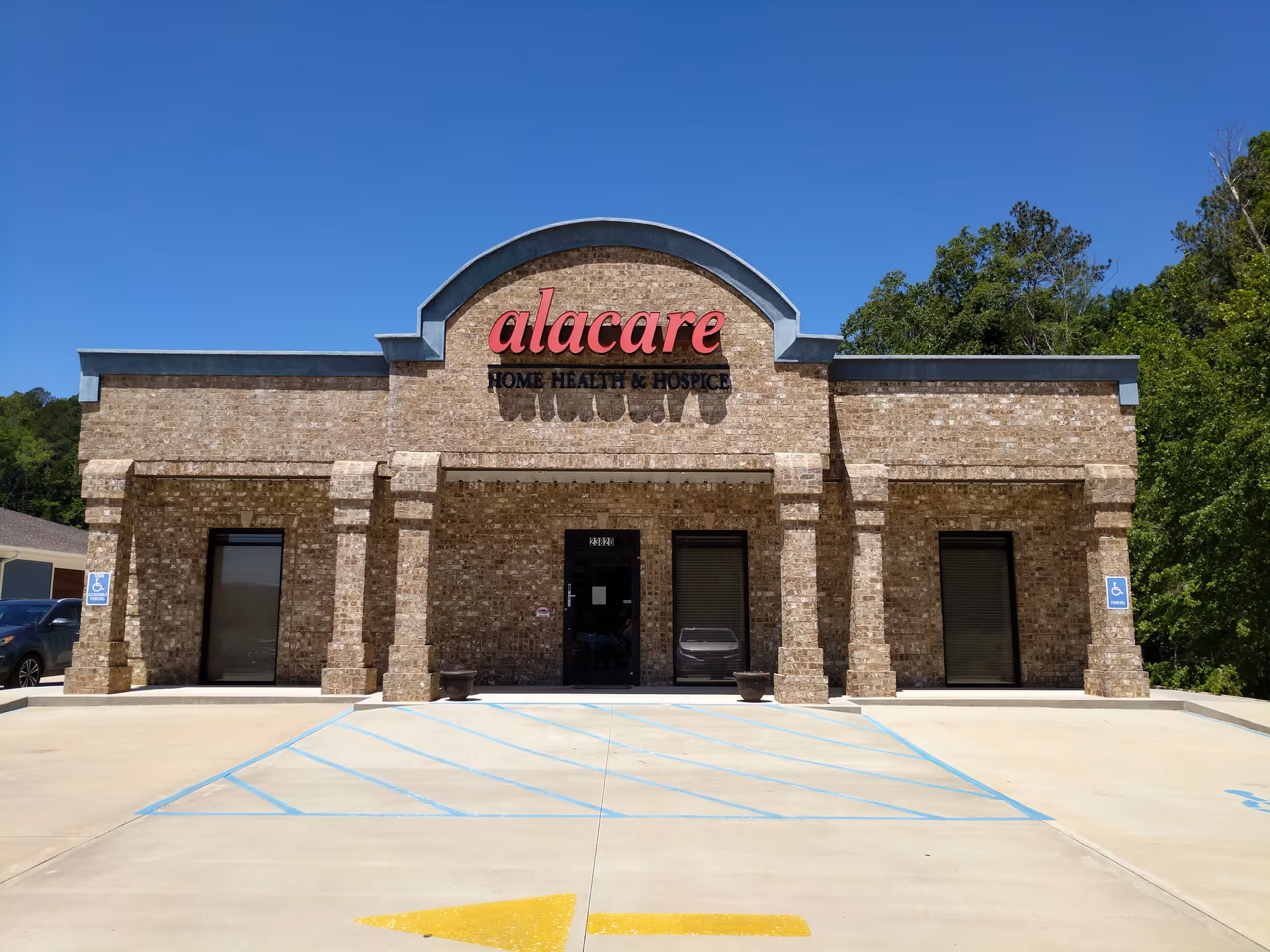 Brick building with an arched sign reading alacare Home Health & Hospice and a parking lot.