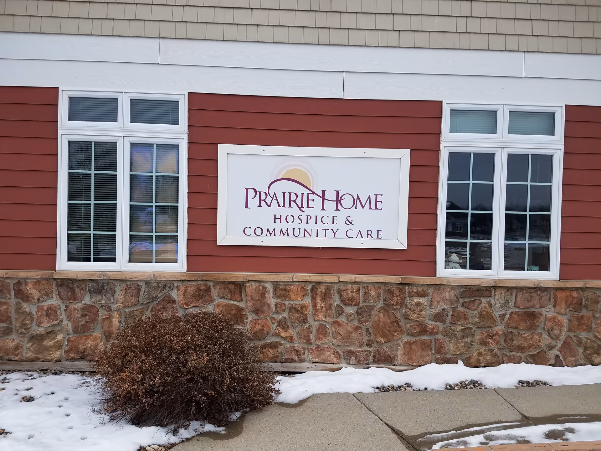 Exterior of Prairie Home Hospice and Community Care building with stone base and red siding