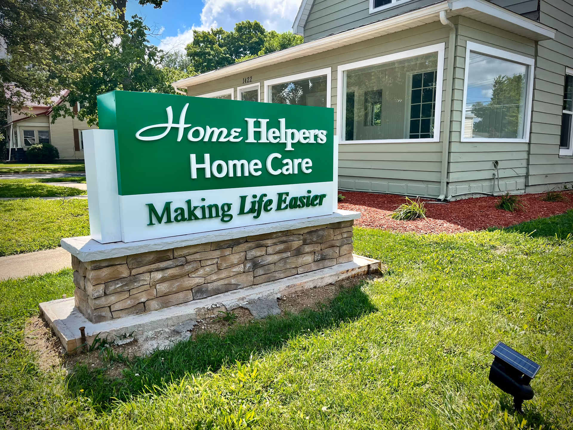Green Home Helpers Home Care sign in front of a gray building with a lawn