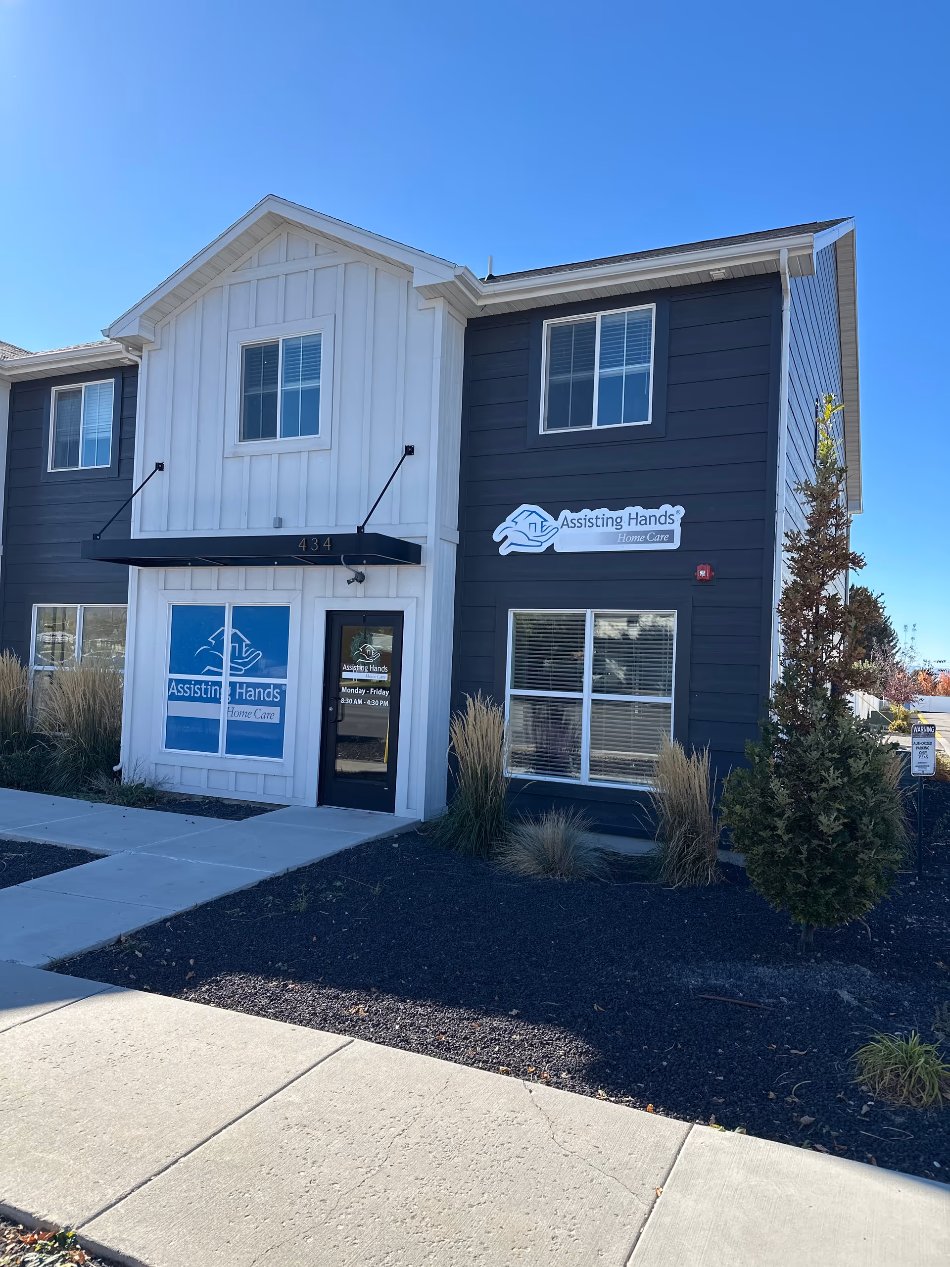 Two-story building with blue-gray siding and Assisting Hands signage at the entrance.