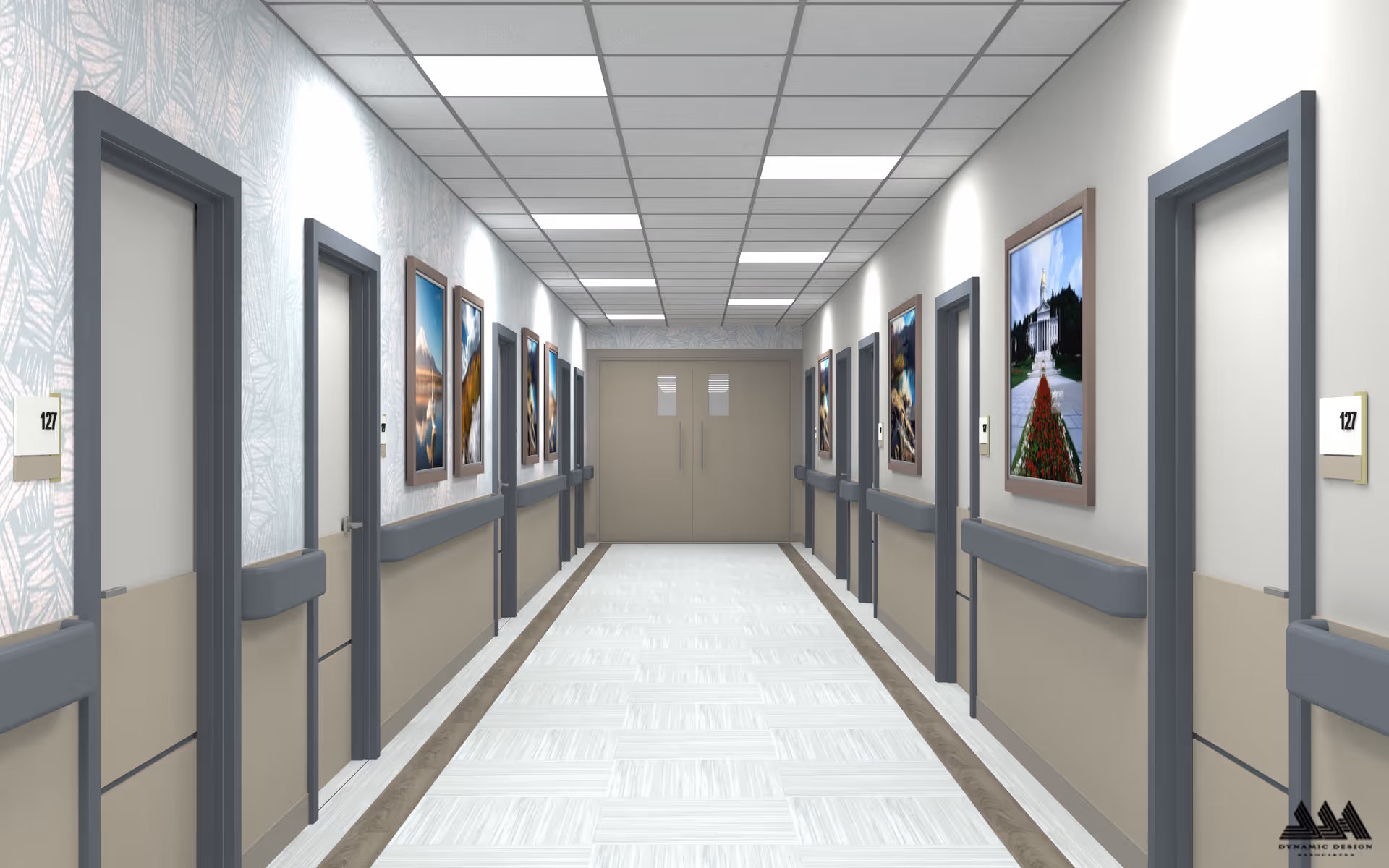 A clean, well-lit hallway in a healthcare facility with multiple closed doors on both sides, each labeled with the number 127. The walls are decorated with framed landscape photographs, and there are handrails along both sides of the corridor. The ceiling has recessed lighting panels, and double doors are visible at the end of the hallway.