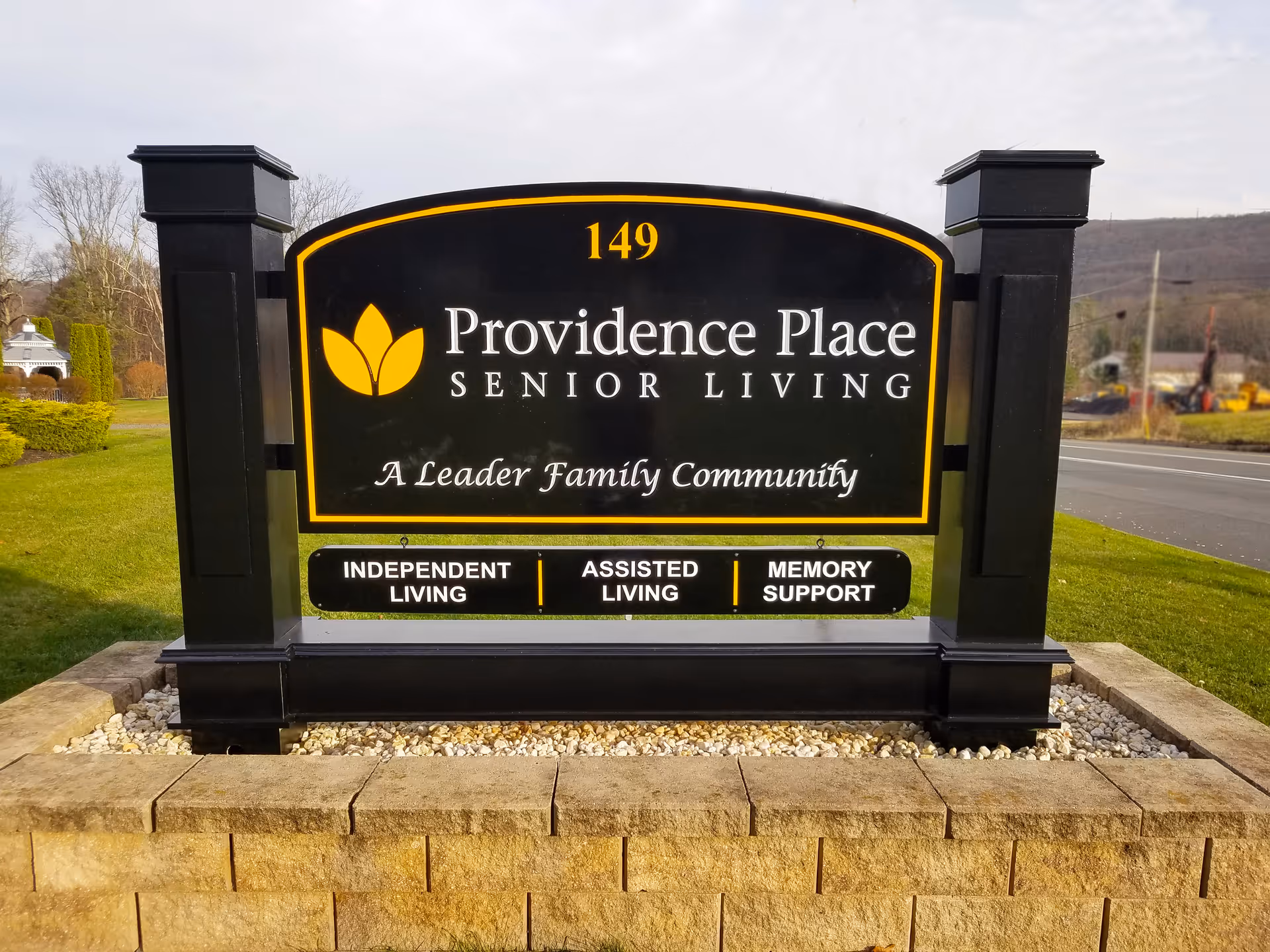 Roadside black-and-gold sign reading "Providence Place Senior Living" with services listed as Independent Living, Assisted Living, and Memory Support.