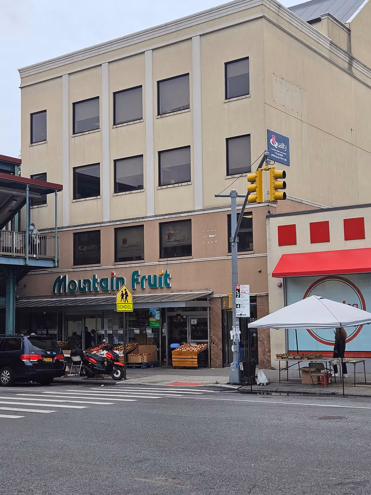 Street view of a beige building with Mountain Fruit storefront and sidewalk market.
