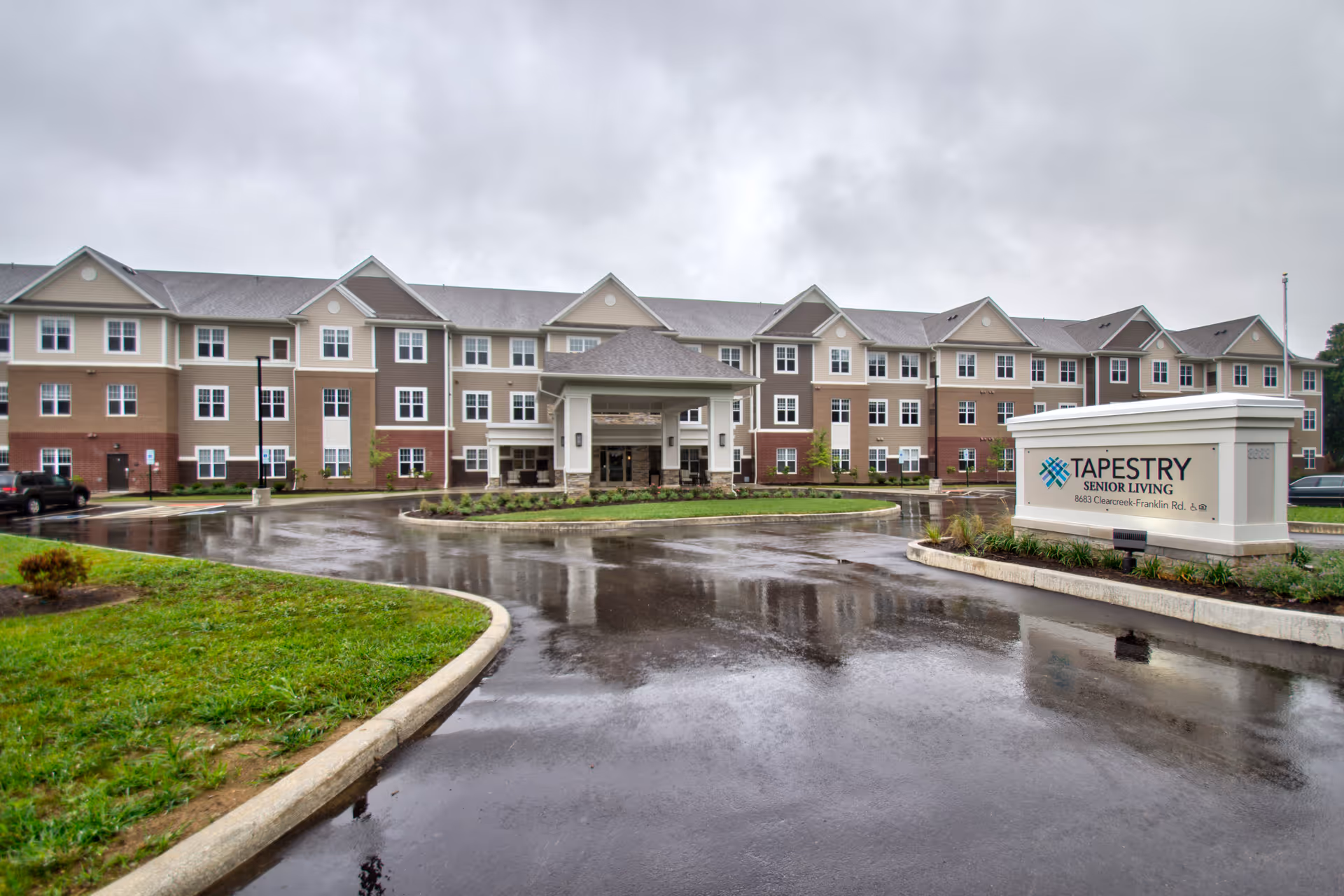 Exterior view of Tapestry Senior Living Springboro with entrance, sign, and wet circular driveway.