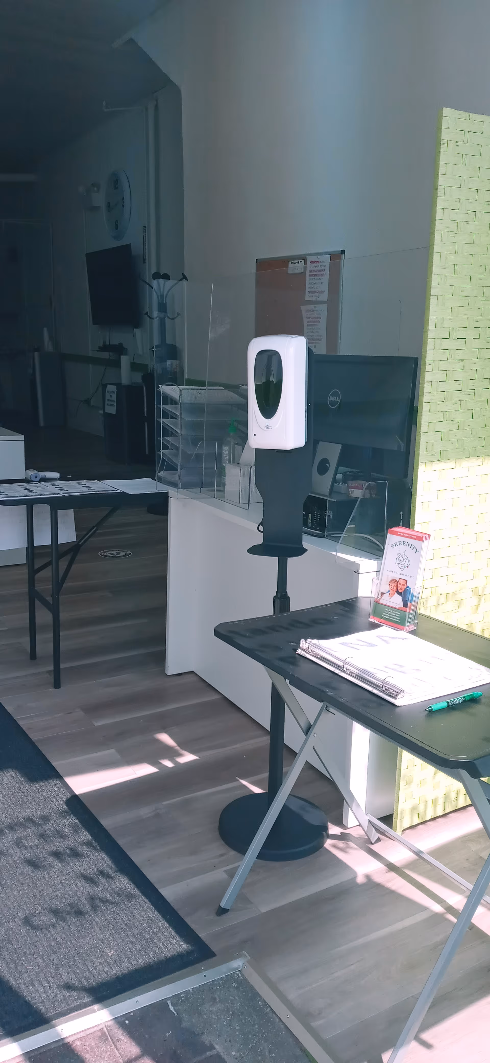 Reception area with sanitizer dispenser, monitor, and brochures inside Serenity Home Healthcare, North Riverside.