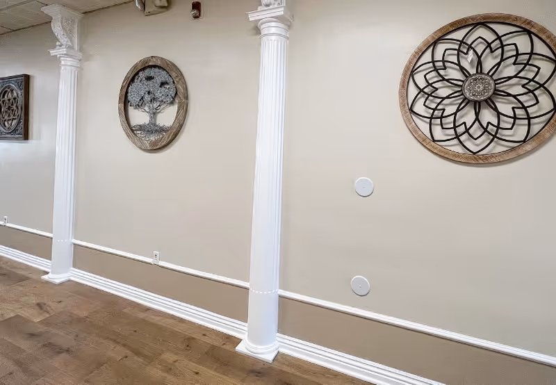 Interior hallway of a senior living facility with white columns and circular wall art.