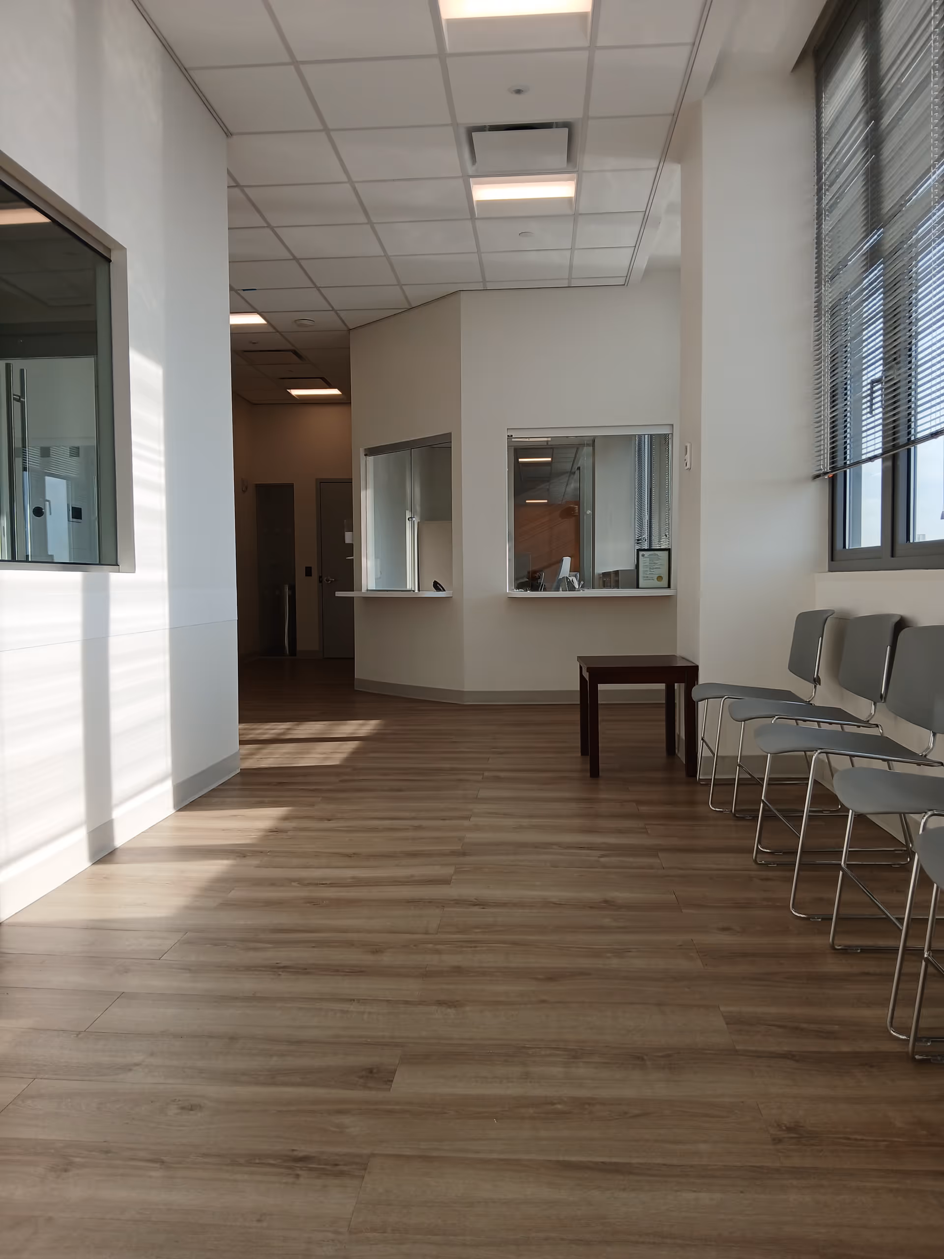 Inside a clean waiting area with chairs, windows, and a reception window in a senior facility.