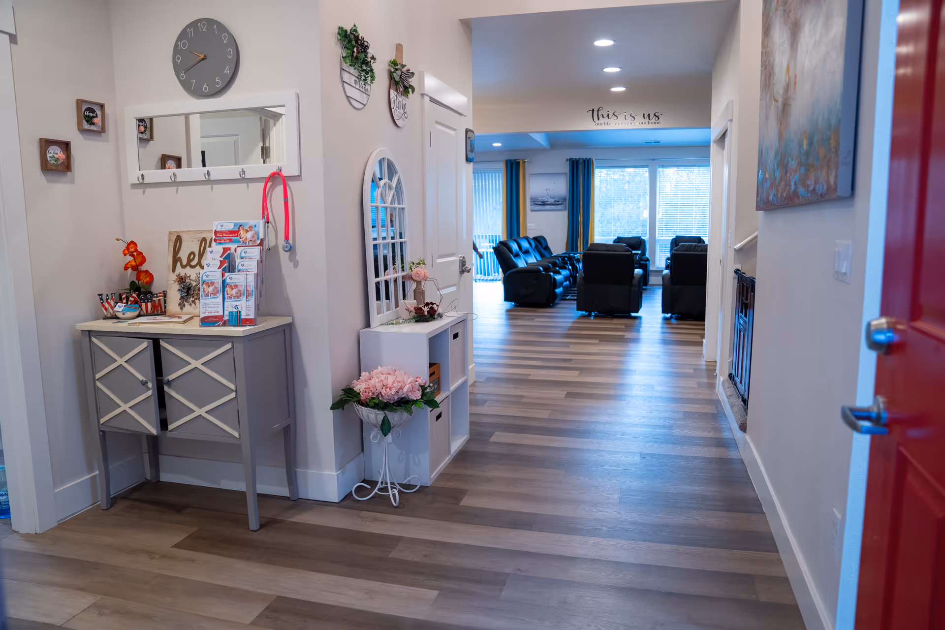 Hallway leads to a lounge area with black recliners in a senior living home.