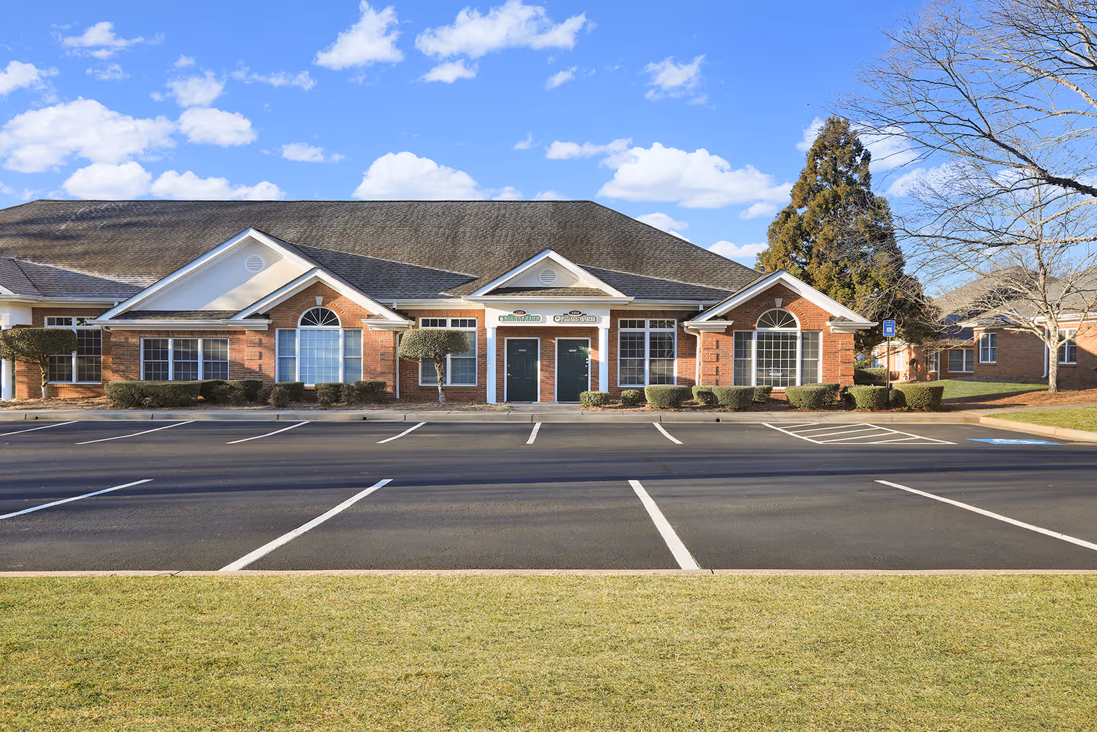 Brick senior living facility with a large front entrance and parking lot.