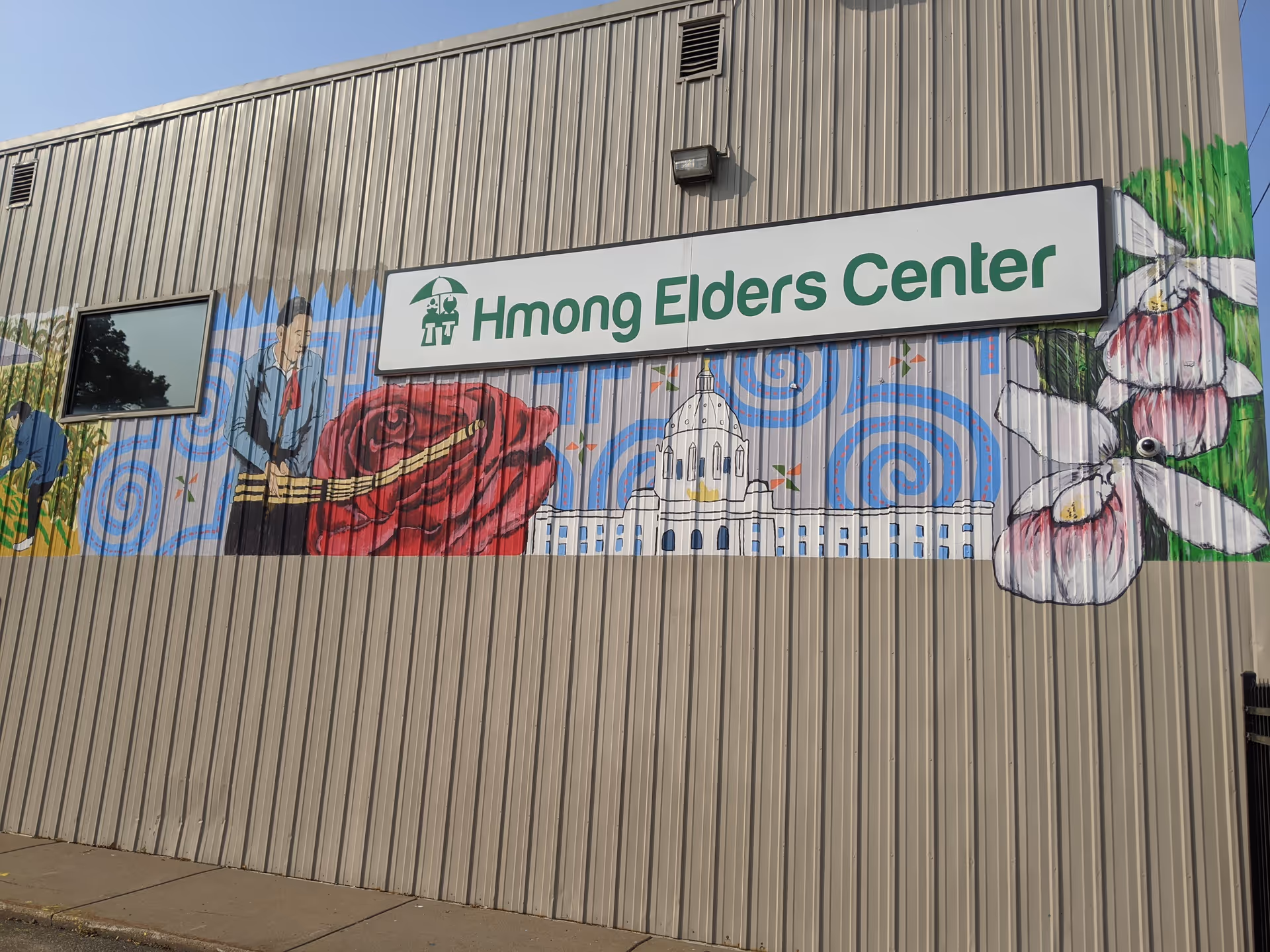 Exterior view of a mural-covered building with a sign reading Hmong Elders Center.