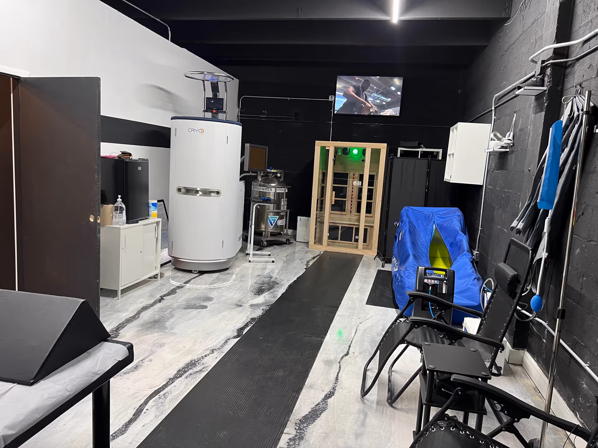 Cryotherapy chamber and therapy equipment are visible in a modern treatment room.