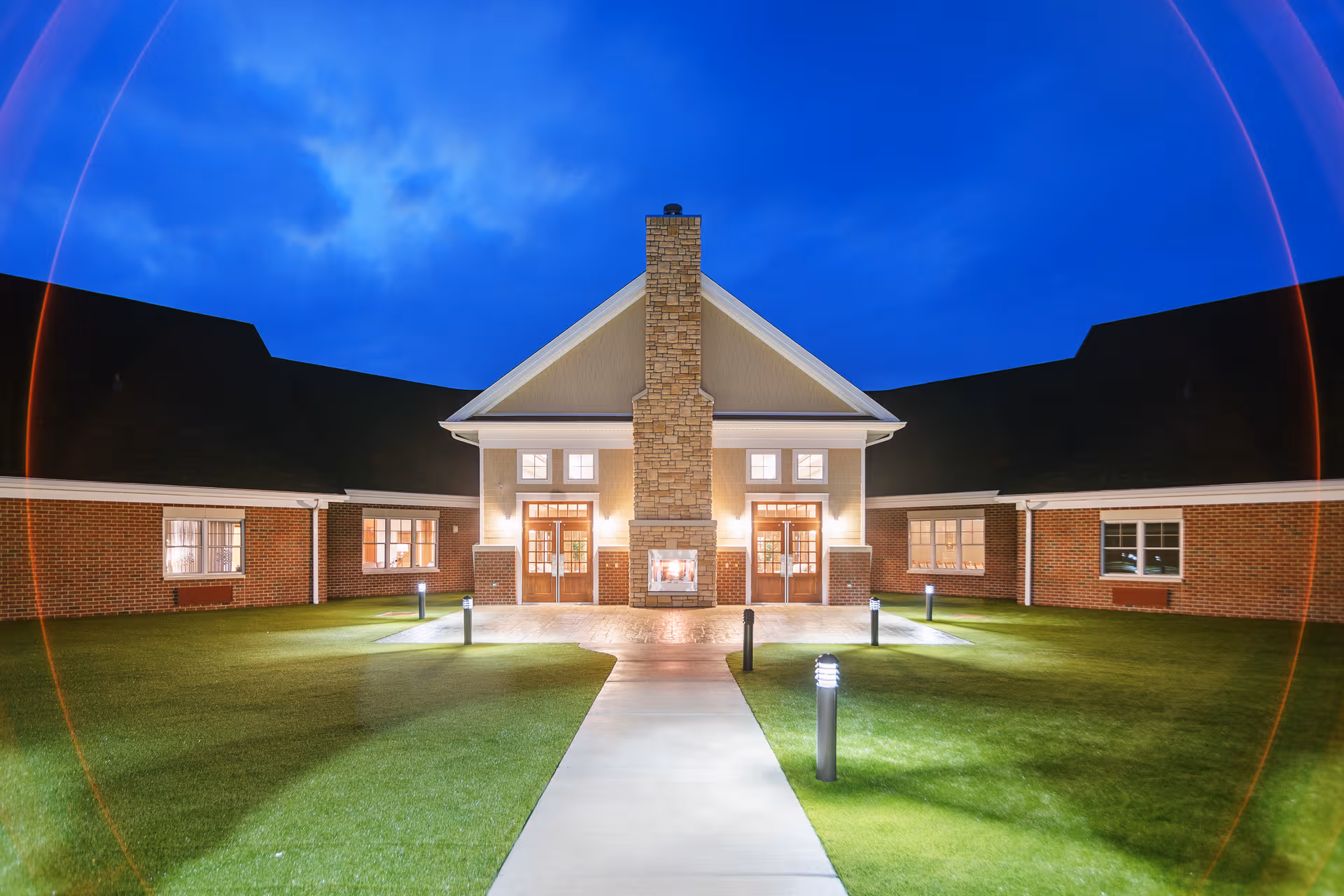 Night exterior view of Armstrong Memory Care Assisted Living building with lit entrance and brick facade
