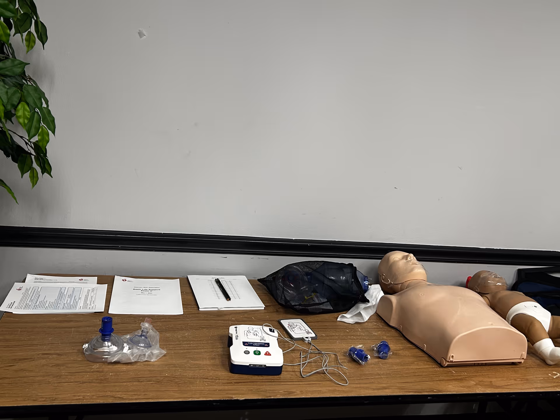 Medical training setup on a table with CPR mannequins, papers, and equipment.