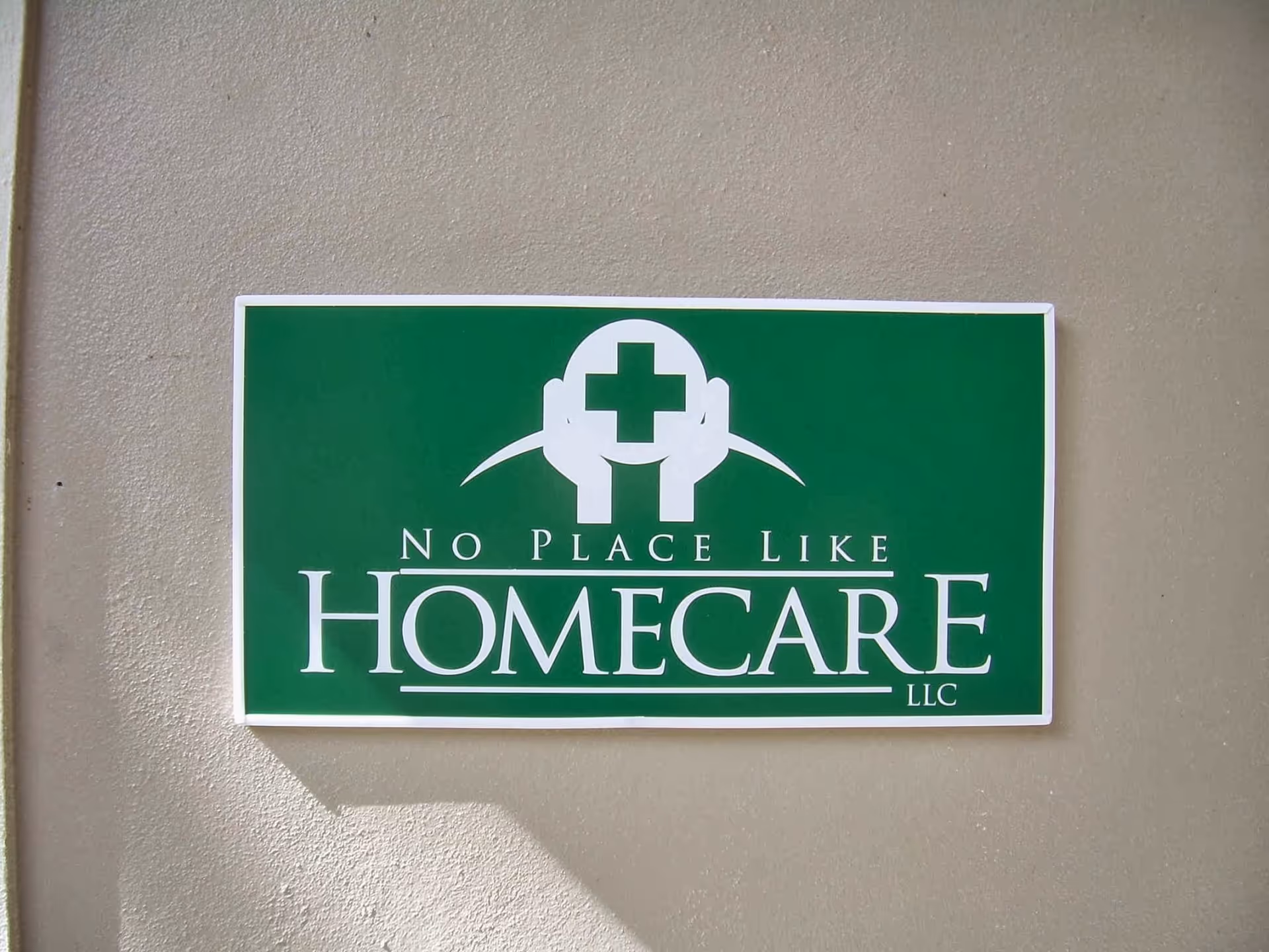 Green No Place Like Homecare LLC sign mounted on beige exterior wall